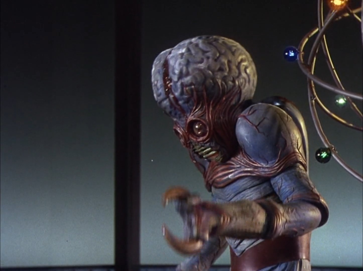 The Metaluna mutant monster, a green skinned beast with crab claws for hands and a huge bulging brain with bulging eyes